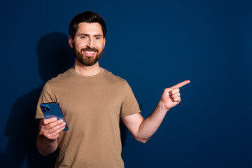 Poster - Photo of young guy brunet in beige t shirt using smartphone direct finger personal website isolated on dark blue color background