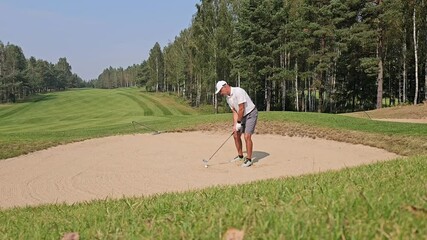 Canvas Print - Golf enthusiast practices sand shots on a sunny day at a beautiful course surrounded by trees