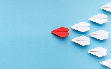 Poster - New trends concept. One red paper plane followed by group of white ones on blue background, copy space