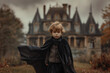 © Babb - A young child wearing a black cape stands in front of a large house