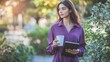 © Suleyman - A woman is walking along a path holding a notebook and a coffee cup. She is wearing a purple blouse and looks professional.
