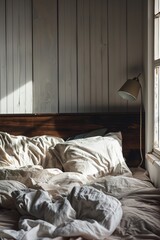 Aufkleber - An unmade bed with messy sheets and blankets in a dark room with a window