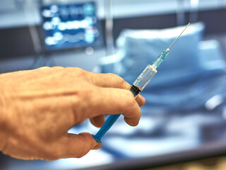 a fragment of a hand holds a syringe for vaccinations