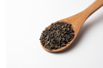 large wooden spoon on a white background. Green leaf tea is poured into a spoon. Tea party concept. Traditional Indian drink, top view. flat lay