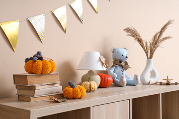 Sticker - Pumpkins with books, lamp and toy bear on shelf near beige wall in children's room