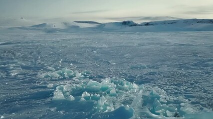 Poster - Turquoise ice formations are surrounded by white ice and snow leading to snow covered mountains in the distance on a sunny arctic day