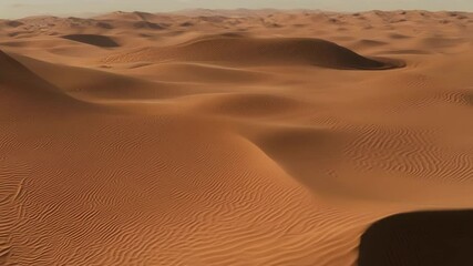Poster - Rolling sand dunes in warm sunlight create mesmerizing light and shadow patterns in a vast desert landscape under a soft blue sky with fluffy clouds