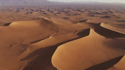 Poster - Basking in warm sunlight. Wind blown sand dunes create a mesmerizing landscape stretching endlessly. With peaks. Valleys. And distant mountains adding to the scenic view of the vast
