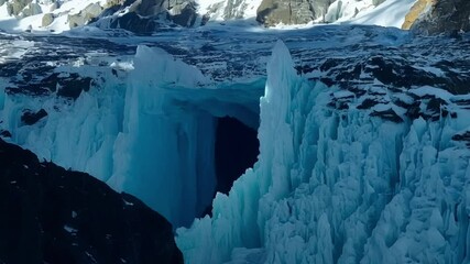 Poster - Stunning blue ice cave on a mountain glacier, illuminated by sunlight, stands out in the snowy landscape, capturing the essence of frozen nature in a remote wilderness