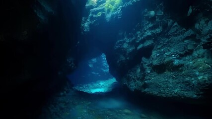 Poster - Diving into a mesmerizing underwater cave with blue water, rock formations, and rays of light, evoking wonder and mystery. Explore the serene, mysterious depths for an unforgettable adventure