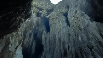 Poster - The sun shines over a narrow passage between towering rocks. Creating a canyon like scenery with high formations casting shadows against the blue sky