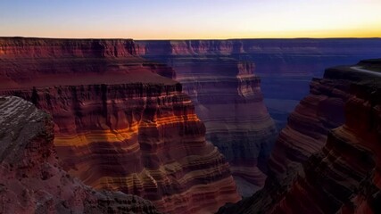 Poster - Warm sunlight is illuminating the colorful layers of rock formations in a canyon landscape, creating a dramatic and awe inspiring scene