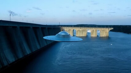 Poster - Mysterious ufo hovers silently at dusk above a dam and river, casting a twilight glow. The futuristic spacecraft adds wonder to the scene, evoking thoughts of unknown technology
