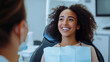 © Frank Gärtner - Smiling woman chats with dentist during check-up in modern clinic, focusing on oral health. African american with curly hair, showing trust and commitment to dental care