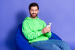 © deagreez - Photo of mature age funky man wearing bright green hoodie holding smartphone and making money ecommerce isolated on violet color background