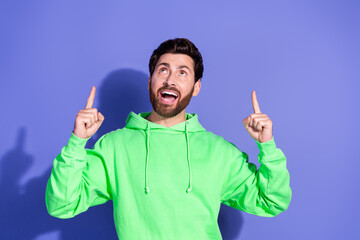 Canvas Print - Photo of handsome mature age funky man wearing bright green hoodie pointing fingers up enjoying empty space isolated on violet color background