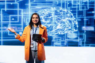 Poster - Cheerful engineer holding presentation at AI tech summit event gathering professionals using tablet. Jolly speaker using device to present how can AI be leveraged to accelerate innovation