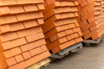 Stacks of new, red ceramic brick stacked on wooden pallets.