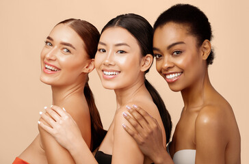 Wall Mural - Skincare And Beauty. Three Mixed Girls Posing Shirtless, Wearing Bra Standing Over Gray Background, Smiling To Camera. Studio Shot