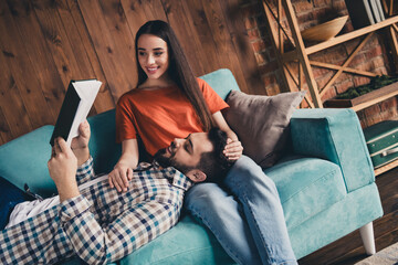 Wall Mural - Photo of cheerful cute young couple sofa lying read book enjoy weekend have fun buy new apartment indoors inside house home