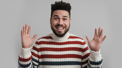 A man with a beard and a red and white striped sweater is smiling and waving