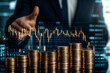 © kongkiat chairat - Businessman giving thumbs up behind stacks of coins with financial stock market graph, concept of investment and economic growth.