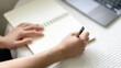 © bunyiam - A person is writing in a notebook with a pen