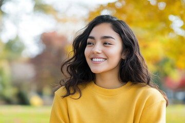 Wall Mural - Hispanic woman wearing yellow knitted sweatshirt in autumn park at sunny day