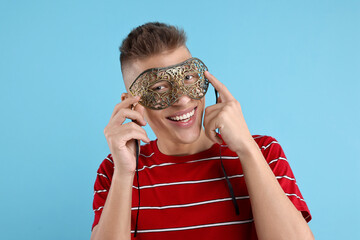 Poster - Charming young man wearing carnival mask on light blue background