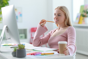 Poster - Designer with paper cup of drink working at table in office