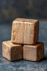 Poster - Close-up of three stacked wooden blocks on a dark background, showcasing natural textures and rustic charm. Perfect for craft or construction themes.