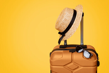 Summer Travel Concept. Suitcase luggage with sun glasses and hat over yellow background, panorama with copy space