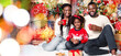 © Prostock-studio - Portrait of cheerful black family celebrating Christmas with milk and cookies, sitting in decorated living room and smiling at camera
