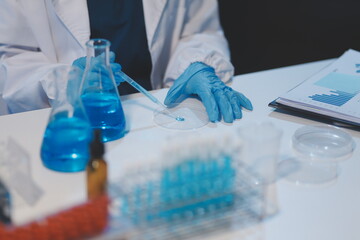 Group of dedicated scientist conduct chemical experiment in medical laboratory, carefully drop precise amount of liquid from pipette into test tube for vaccine drug or antibiotic development. Neoteric