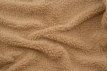 Soft beige fleece fabric draped elegantly on a flat surface in natural light