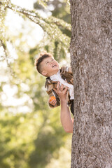 Wall Mural - Boy smiling while man holding him up behind the tree