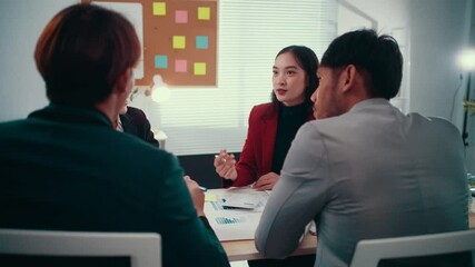 Poster - Businesswoman is gesturing while leading a discussion with her colleagues during a briefing. They are sitting around a table in a modern office