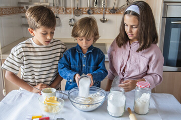 Happy Kids Baking Cookies In The Kitchen, Adding Ingredients And Mixing Dough With Joy And Positive Family Emotions