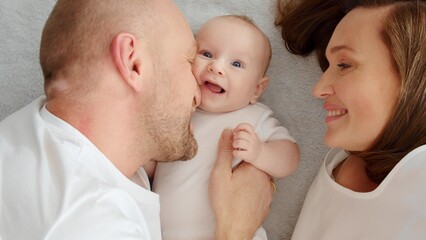 Happy parents with his newborn baby, top view. Happy family. Healthy newborn baby with mom and dad. Close up Faces of the mother, father and infant baby. Cute Infant boy and parents.