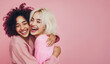 © rakT - Two young women are having fun and friends are hug over pink background