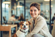 © PixelGallery - Friendly Office Day with a Woman and Her Playful Dog. A young Caucasian woman with long hair enjoys a cheerful moment with her small brown and white dog in a modern office.