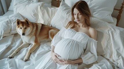 A pregnant woman in a flowing white dress lies on a bed with a loyal dog by her side, creating a serene and affectionate scene.