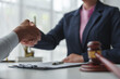 © crizzystudio - Lawyer shaking hands with client after agreement on business contract hammer of justice Customers shake hands after instructions in the office Legal service concept.