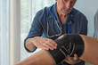© Doodeez - Doctor Consultant examines a patients Knee injury at an accident and emergency appointment. Wearing a Knee support for pain relief after bone fracture accident.