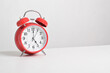 © Mulad Images - Red alarm clock set at five o'clock on table isolated on white background close-up with clipping path