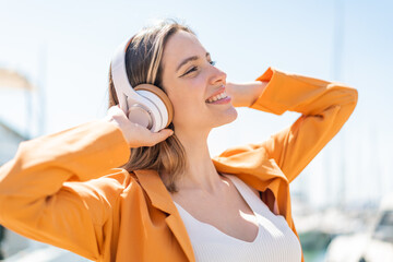 Wall Mural - Young pretty woman at outdoors listening music