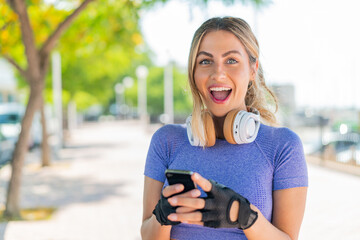 Wall Mural - Young pretty sport woman at outdoors surprised and sending a message