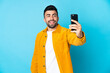 © luismolinero - Caucasian man over isolated blue background making a selfie with mobile phone