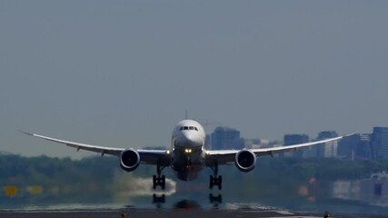 a passenger plane lifting off the runway, with a city skyline in the background under a clear sky