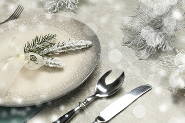 Plate, cutlery and Christmas decor on light grey table, closeup. Bokeh effect